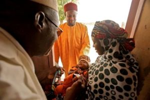  A health worker visits a house and vaccinates an infant. During supplementary immunization activities, health workers walk from house to house, vaccinating every child under five. Tom Moran/WHO
