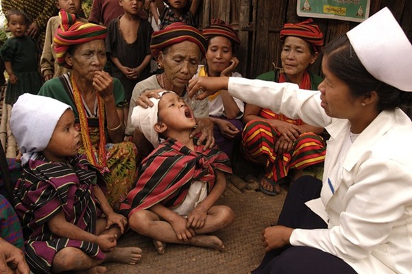 Children and elderly women watch community health worker Daw San Yee (right) vaccinate a child against polio in Kan Thar Yone Village in the western state of Chin in Myanmar.