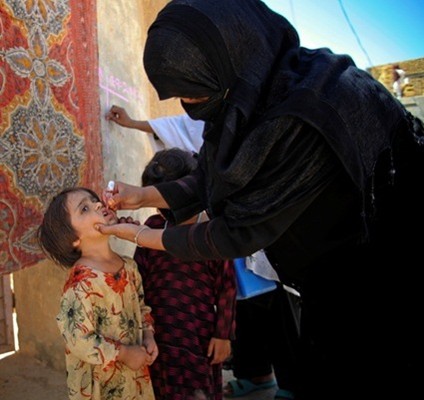 A woman health worker in Baluchistan, Pakistan, gives a child the oral polio vaccine.