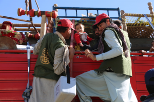 Two vaccinators climb onto a truck to deliver polio vaccines to a family travelling across Torkham border into Afghanistan. © WHO/S. Ramo