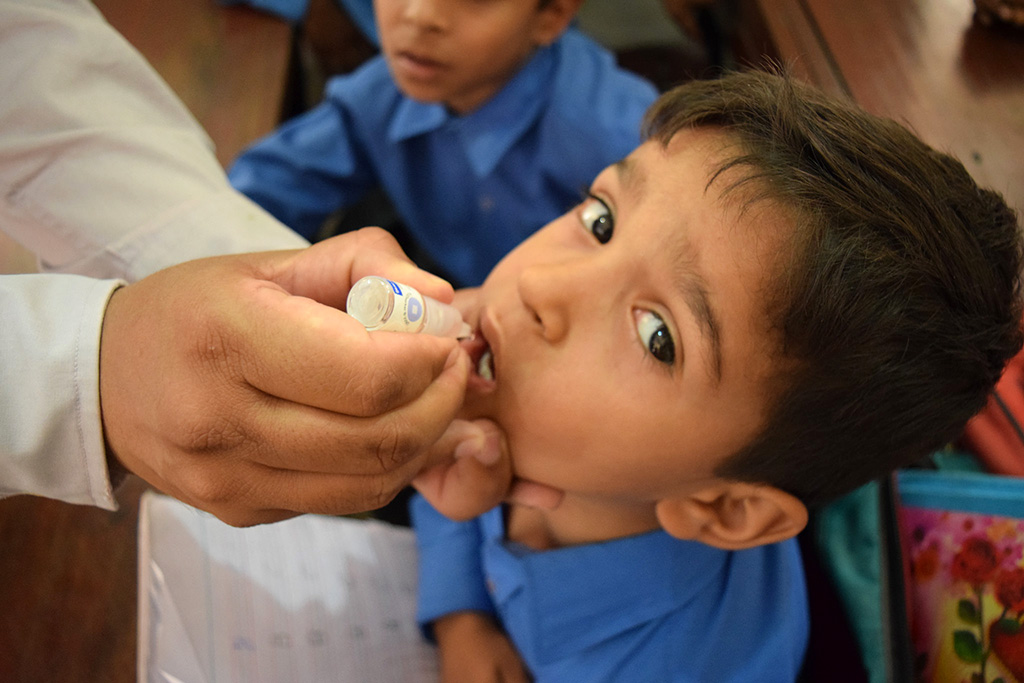 A boy getting vaccinated against polio in school during a campaign in Lahore, Pakistan in May 2018. © WHO EMRO / Anam Khan