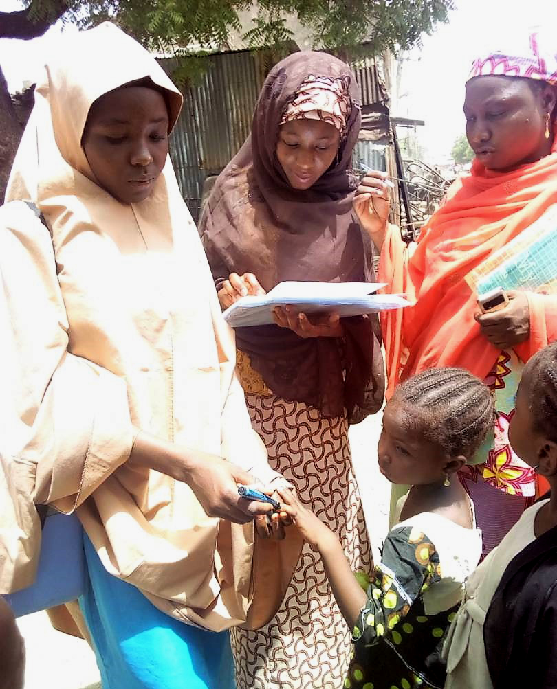 Binta marks a girl’s finger with indelible ink after vaccinating her in Kano State, Nigeria. © WHO Nigeria