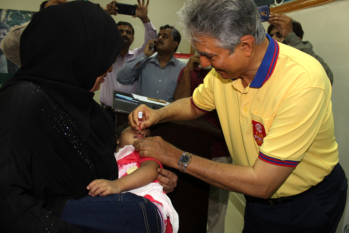 The Rotary National Chair gives a child oral polio vaccine, protecting her against the virus for life. © WHO Pakistan