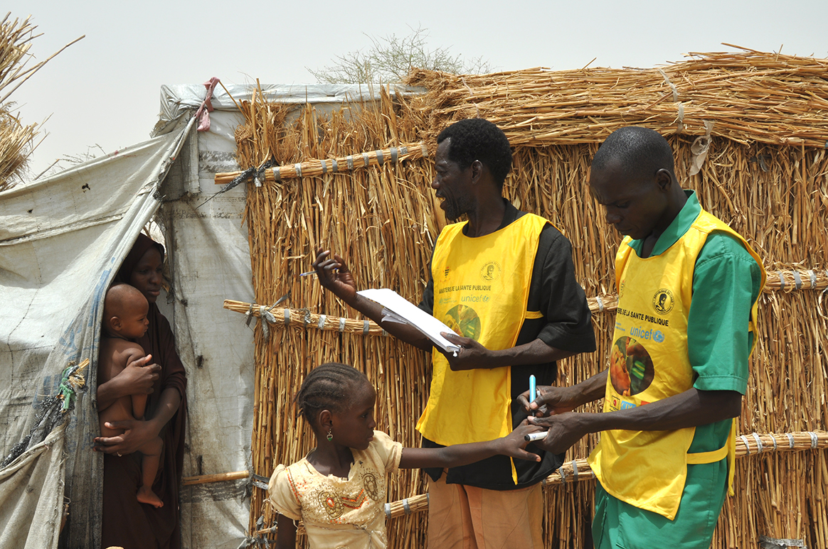 Laurence (centre) explains why vaccination is so important, whilst his colleague marks the finger of a child just vaccinated. © WHO/D. Levison