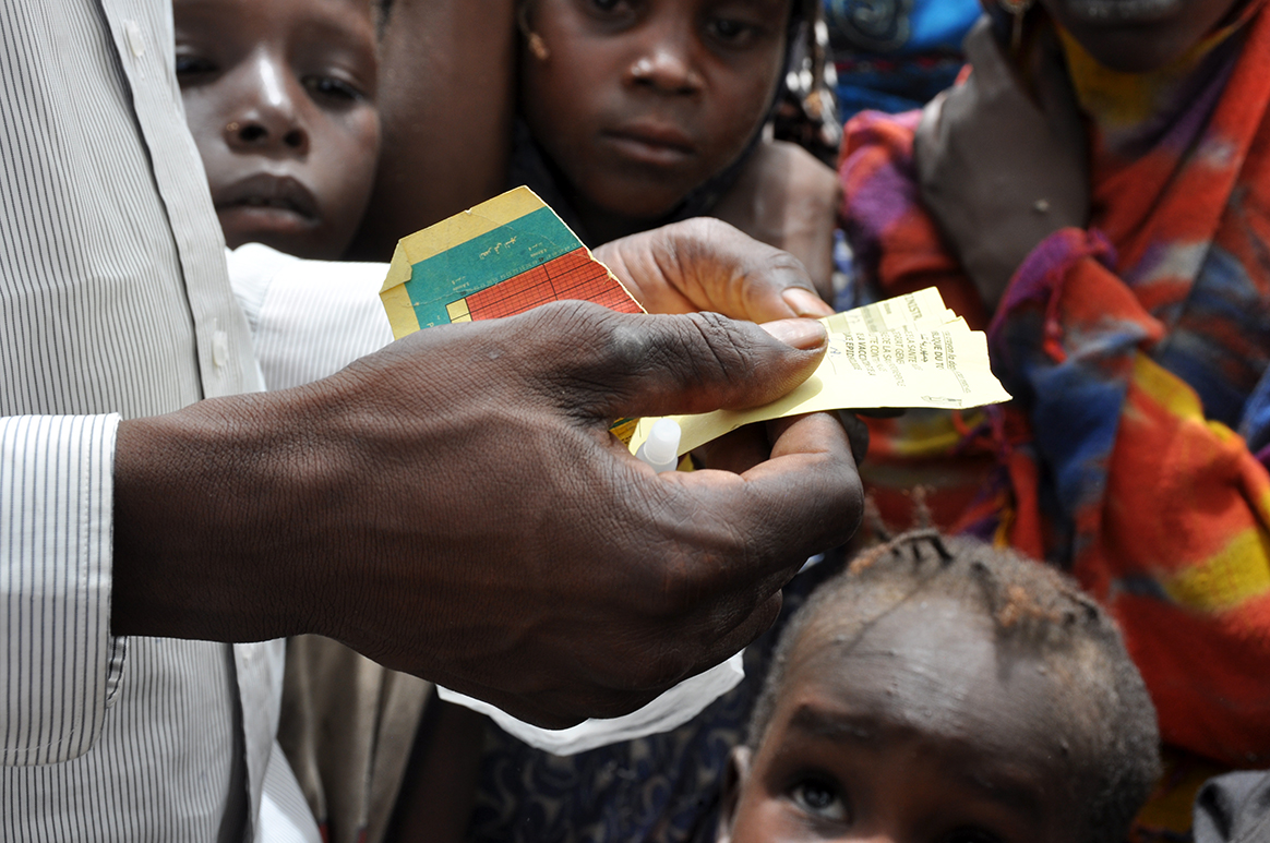 A UNICEF health worker inspects the baby’s vaccination card. © WHO/D. Levison