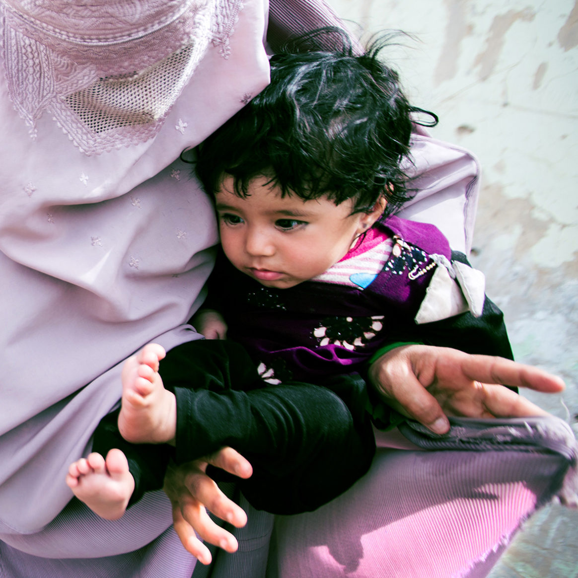 Afia holds a young child who has just received a polio vaccination. The polio eradication programme is one of the biggest female work forces in Afghanistan. © UNICEF Afghanistan