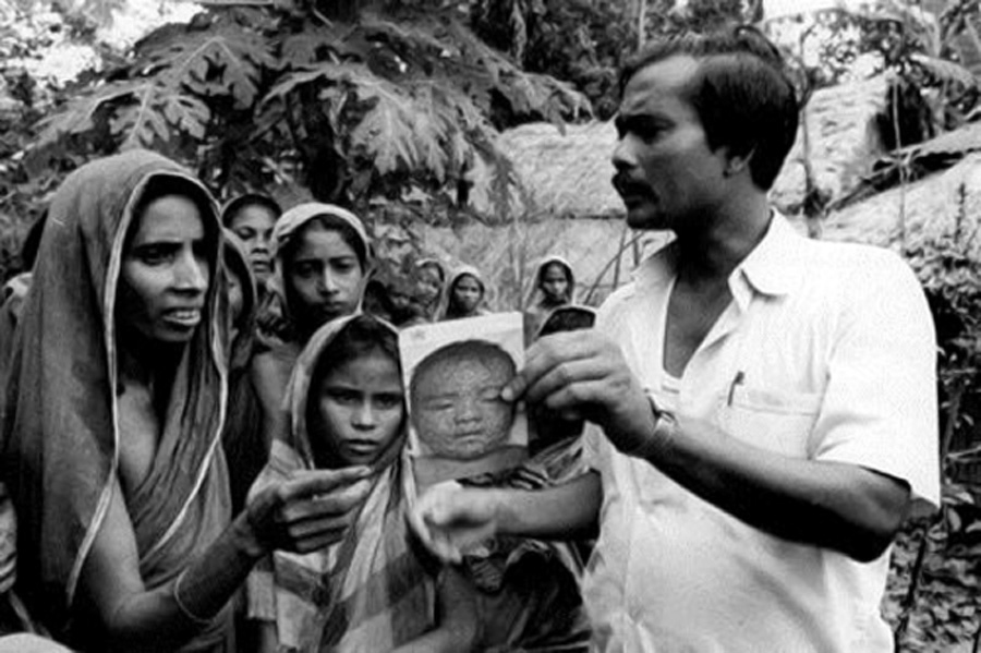 A health worker shows a smallpox recognition card to women in a village, Bangladesh, 1975. © WHO