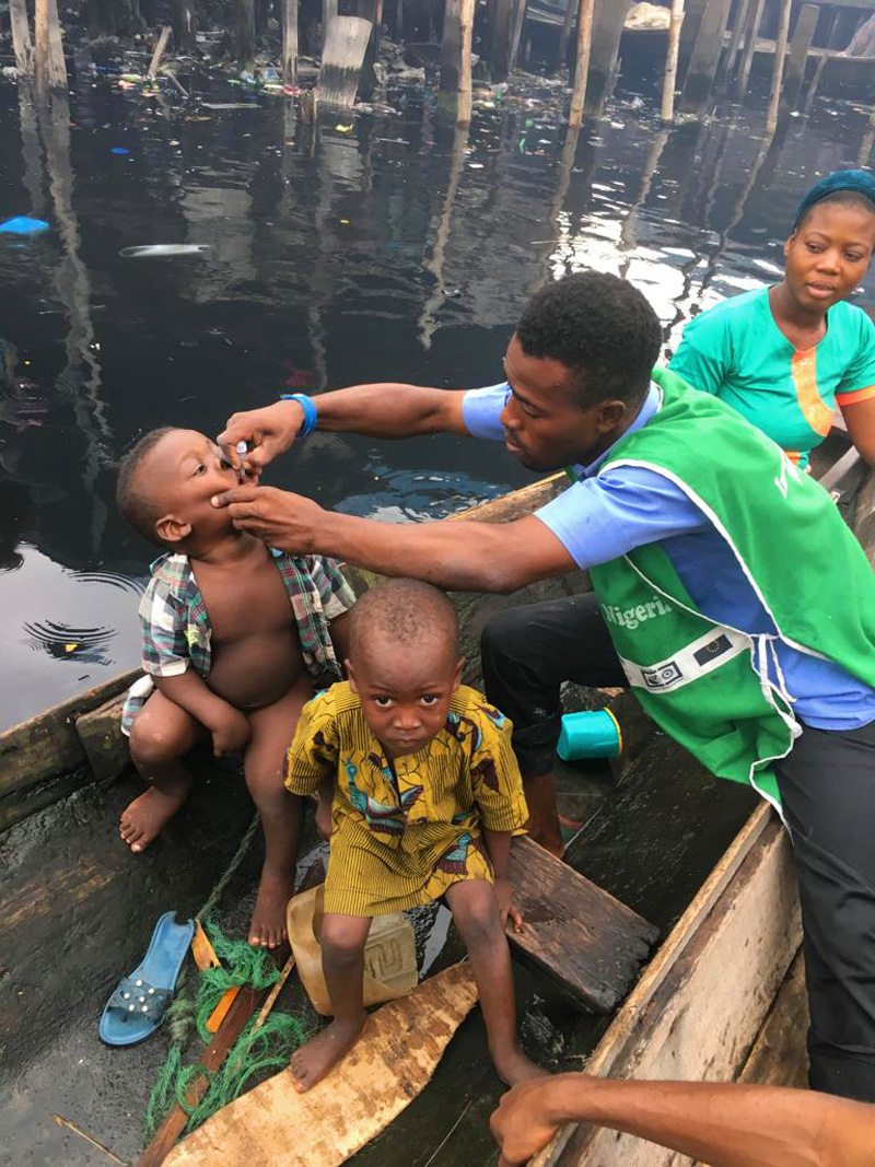 Immunizing a small boy on a canoe as they ferry across their village, Makoko. © UNICEF/Peter Idowu