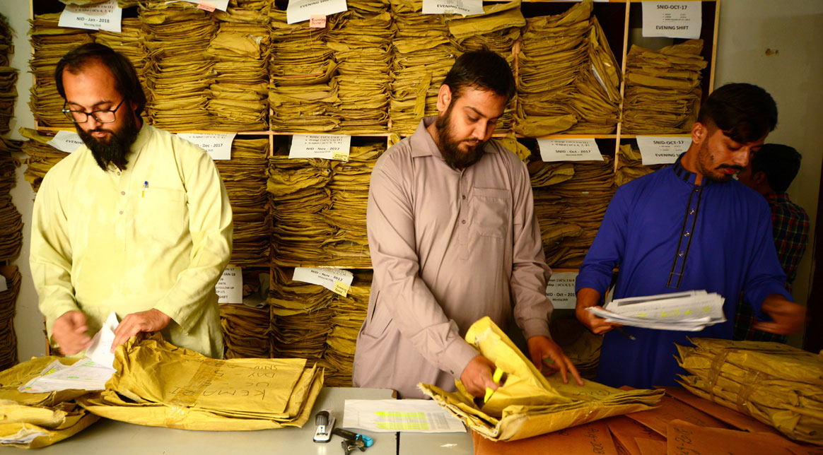 (L-R): Jan Sayyed, Ali Raza and Muhammad Bilal Wasi Jan sifting through thousands of forms from across the country. © Mobeen Ansari