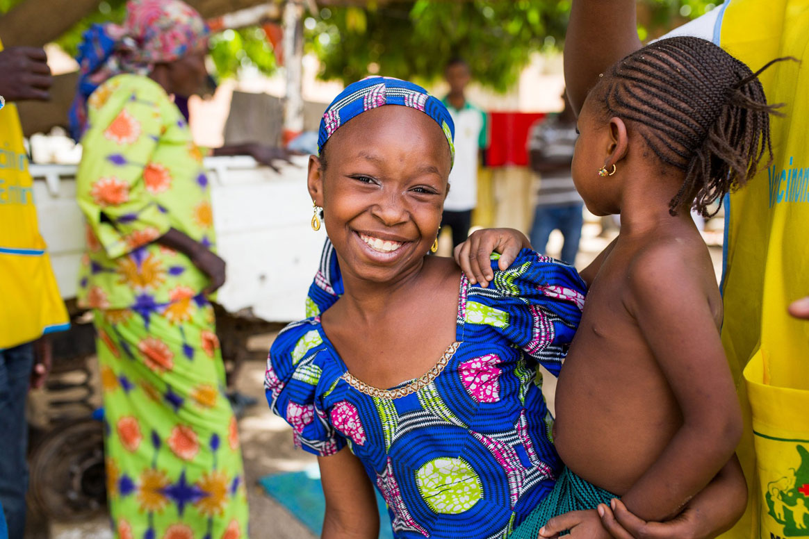 Three-year-old Madsa is carried by her sister after receiving a polio vaccine during a door-to-door campaign in Maroua, Cameroon. ©Gates Archive/Dominique Catton