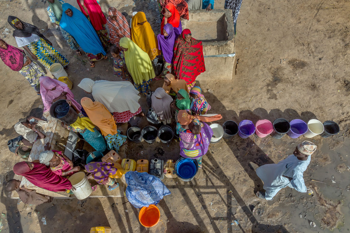 Women and children collect water from a borehole in the Madinatu settlement, where about 5000 displaced people live. © Rotary International