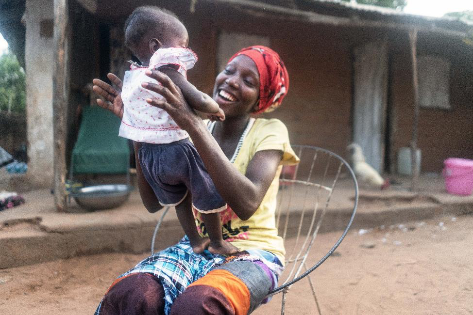 Awa plays with her baby, Abdoulay, after he was vaccinated during the a polio vaccination campaign in Jenoi, The Gambia, on 21 March 2022. Photo: © UNICEF/UN0623991/Lerneryd