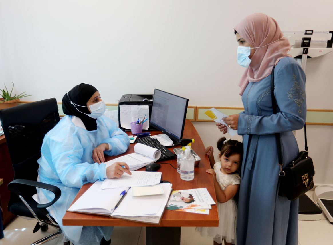 Tamam Taha, a nurse at the Biddo UNRWA health facility, greets a mother at the campaign registration desk. © WHO/occupied Palestinian territory