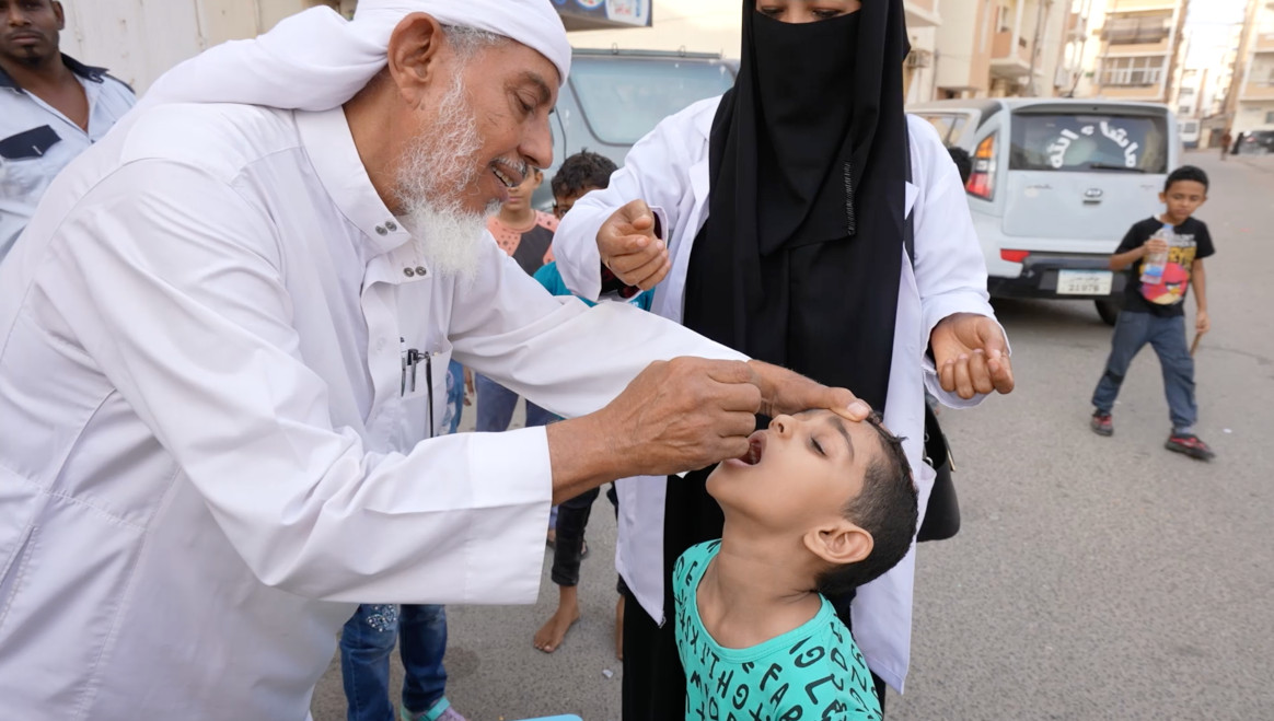 Dr. Nabil vaccinating administering polio drops to one of his grandsons in front of the community to convince people about the safety of the polio vaccine. © UNICEF Yemen 