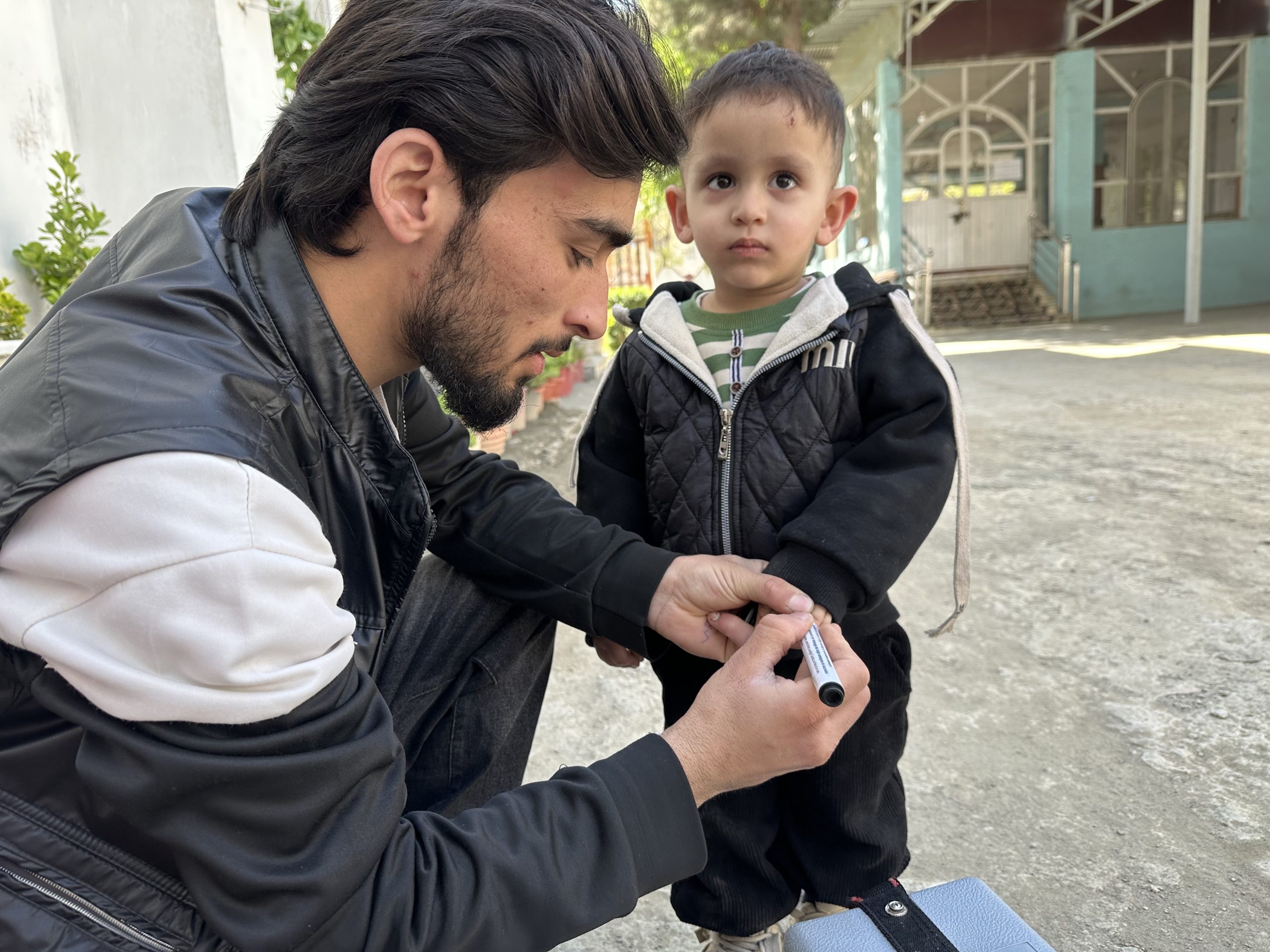 Rostam Mohebi, a polio vaccinator, marks a child’s finger after polio vaccination during the April 2026 National Immunization Days (NID) in Kabul, Afghanistan. © Khesraw Omid Farooq / WHO Afghanistan.